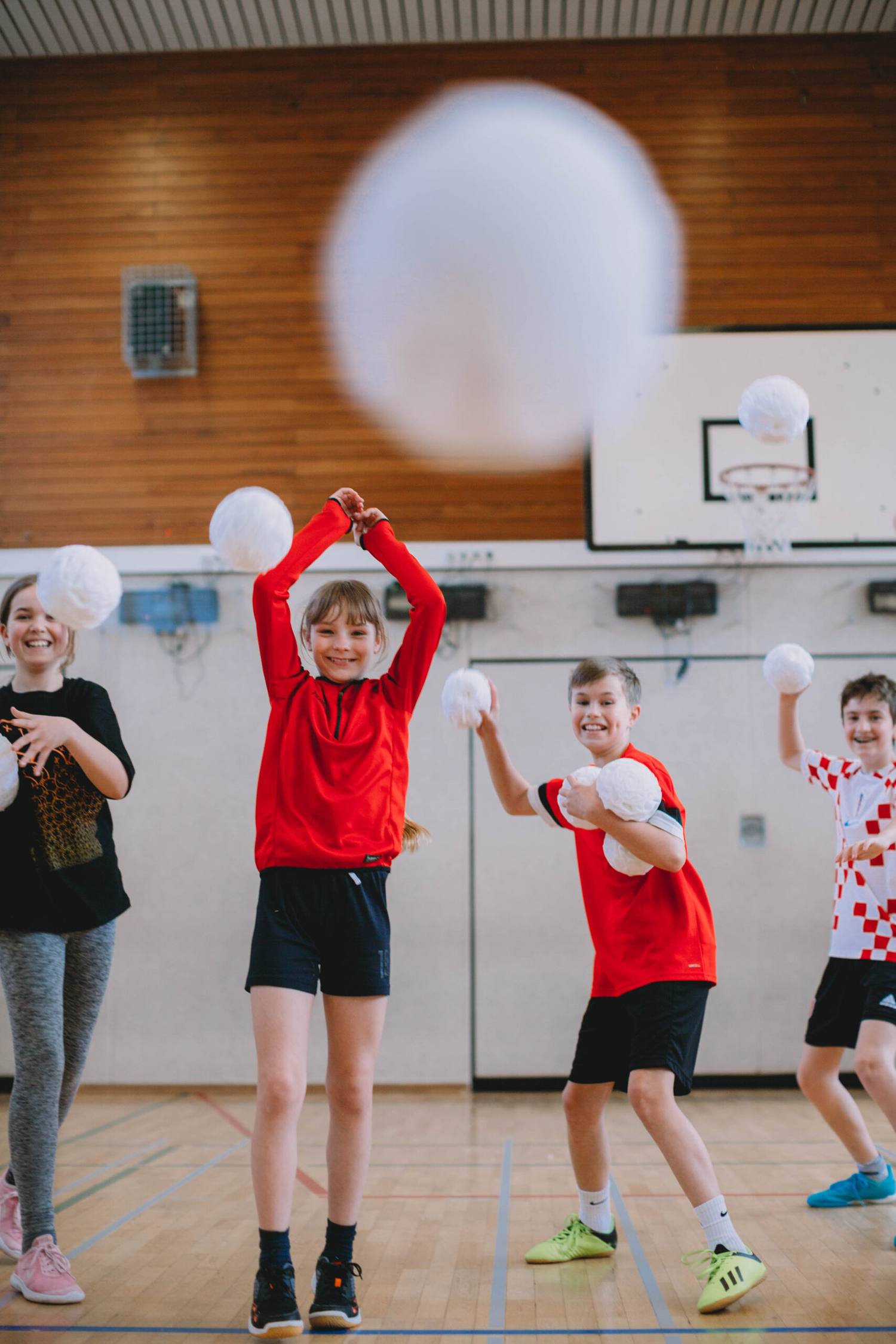Children throwing white Dry Snowballs in a school gym